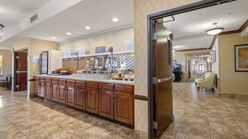 A hotel kitchen with a central island, wooden cabinets, and a breakfast bar.