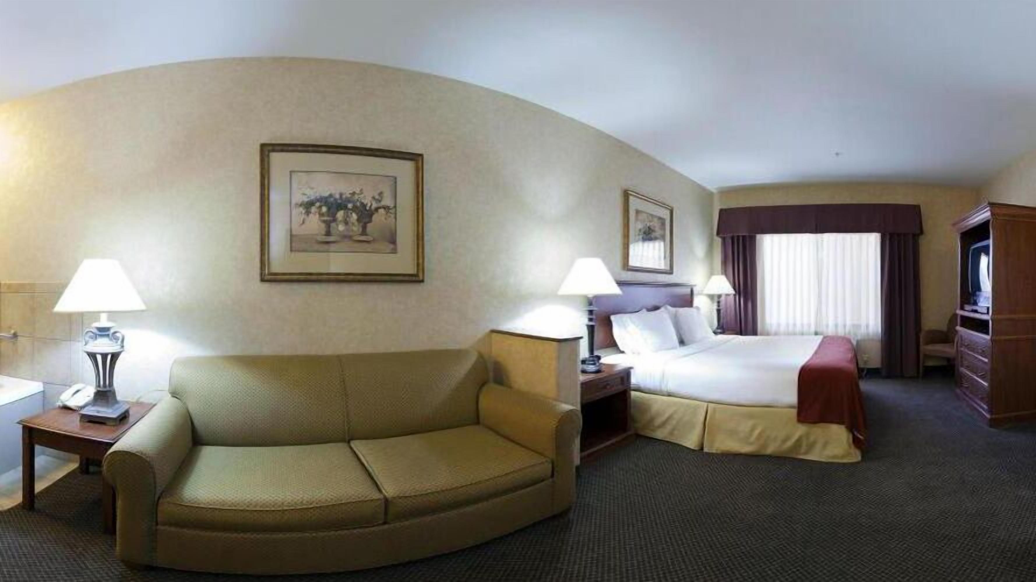 A hotel room with a sofa, a bed, a desk, and a television.
