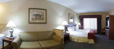 A hotel room with a sofa, a bed, a desk, and a television.