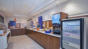 A modern kitchen with a yogurt dispenser, a coffee machine, and a fruit bowl.