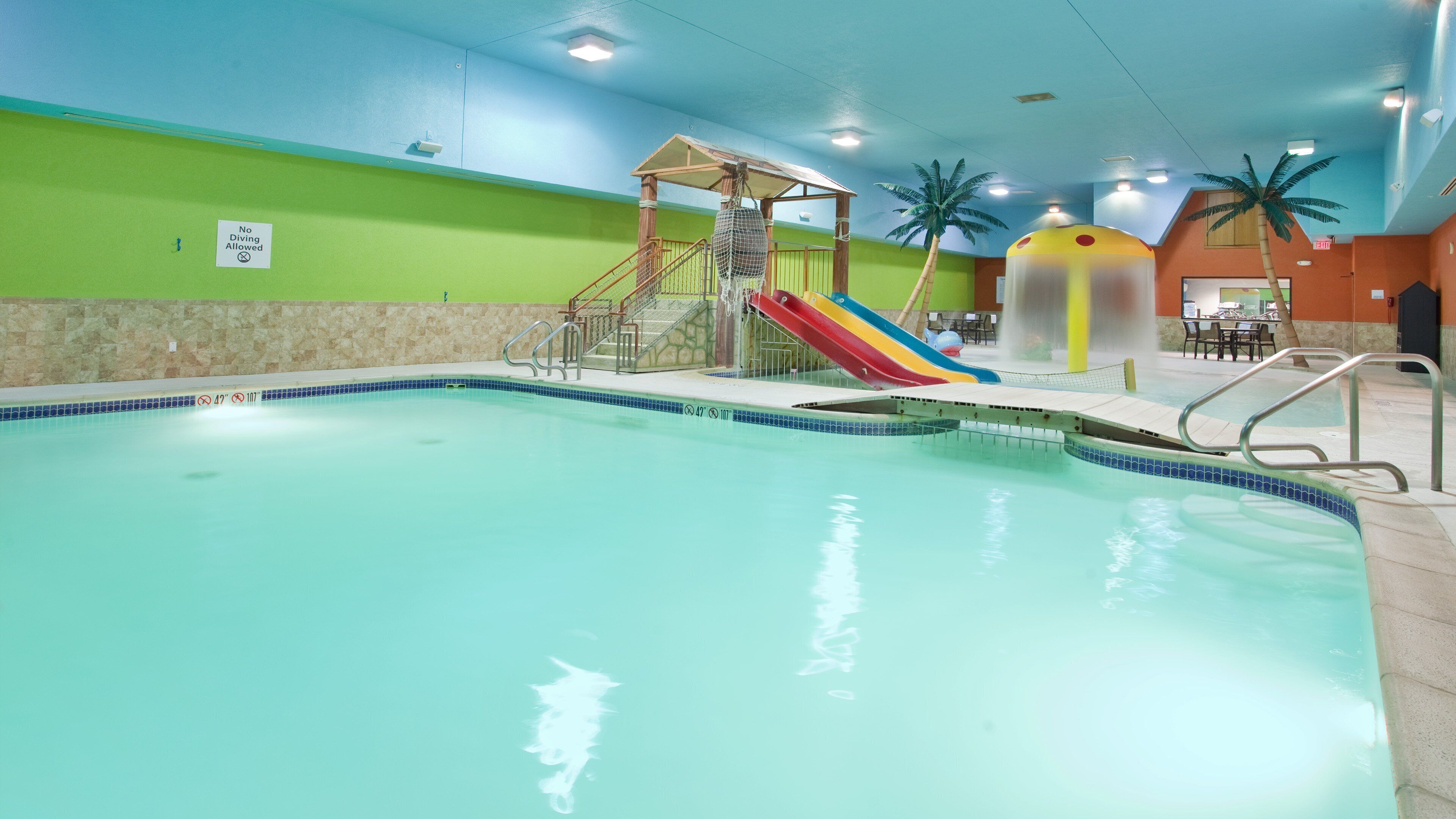 An indoor swimming pool with a slide and a children's play area.