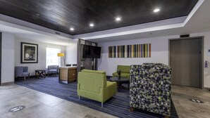 Un moderno vestíbulo de hotel con recepción, zona de estar y televisión.