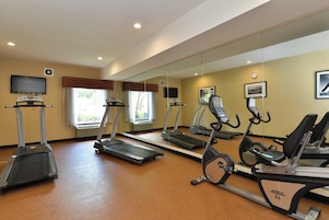 A gym with treadmills, stationary bikes, and a television.