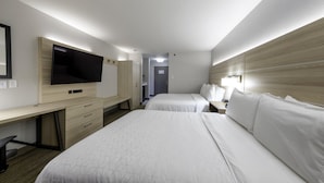 Habitación de hotel con dos camas, un escritorio con televisión de pantalla plana, un armario y una mesita de noche con lámpara.