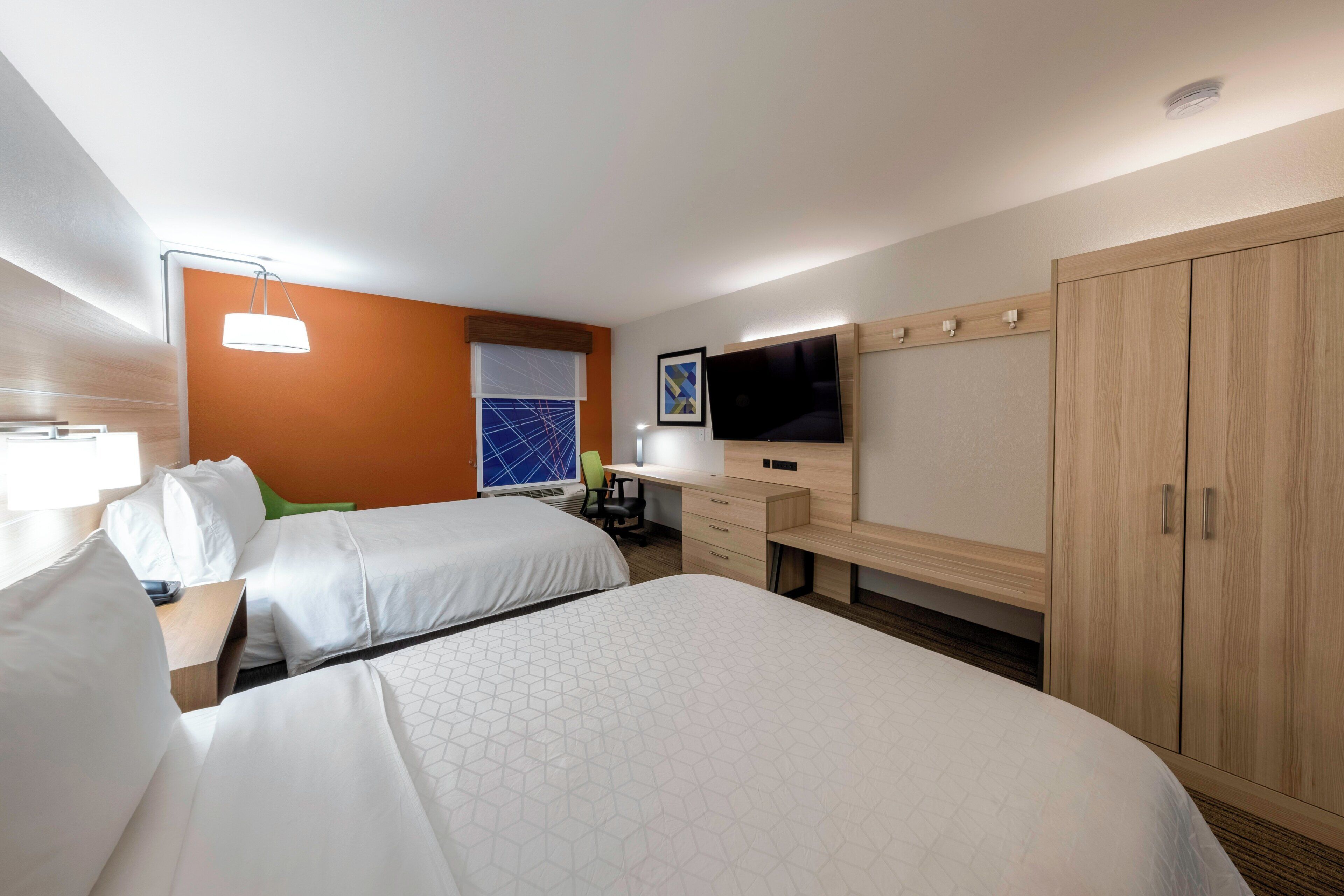 A hotel room with two beds, a desk, a television, and a wardrobe.