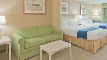 A hotel room with a green sofa, a single bed, a nightstand, and a small table.