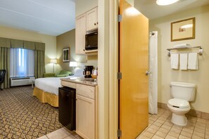 Habitación de hotel con cama, kitchenette y baño.