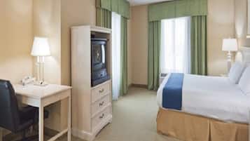 A hotel room with a bed, a desk, a chair, a wardrobe, and a television.