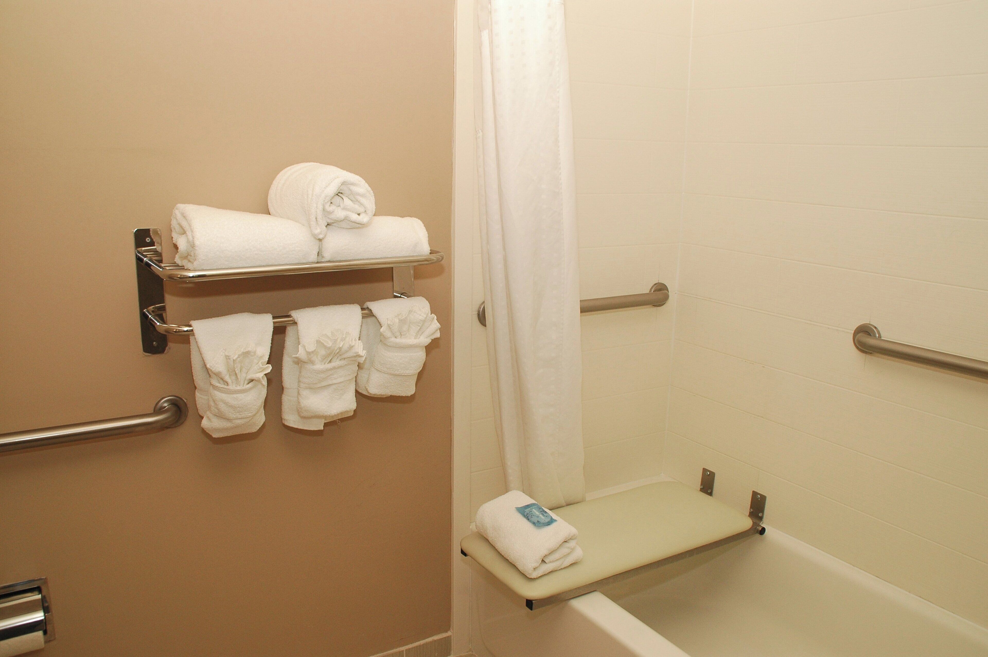 Une salle de bain équipée d’un porte-serviettes, d’un rideau de douche et d’une barre d’appui.