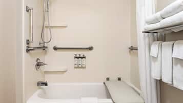 Un baño con bañera, ducha, barras de apoyo, toallero y dispensador de jabón.