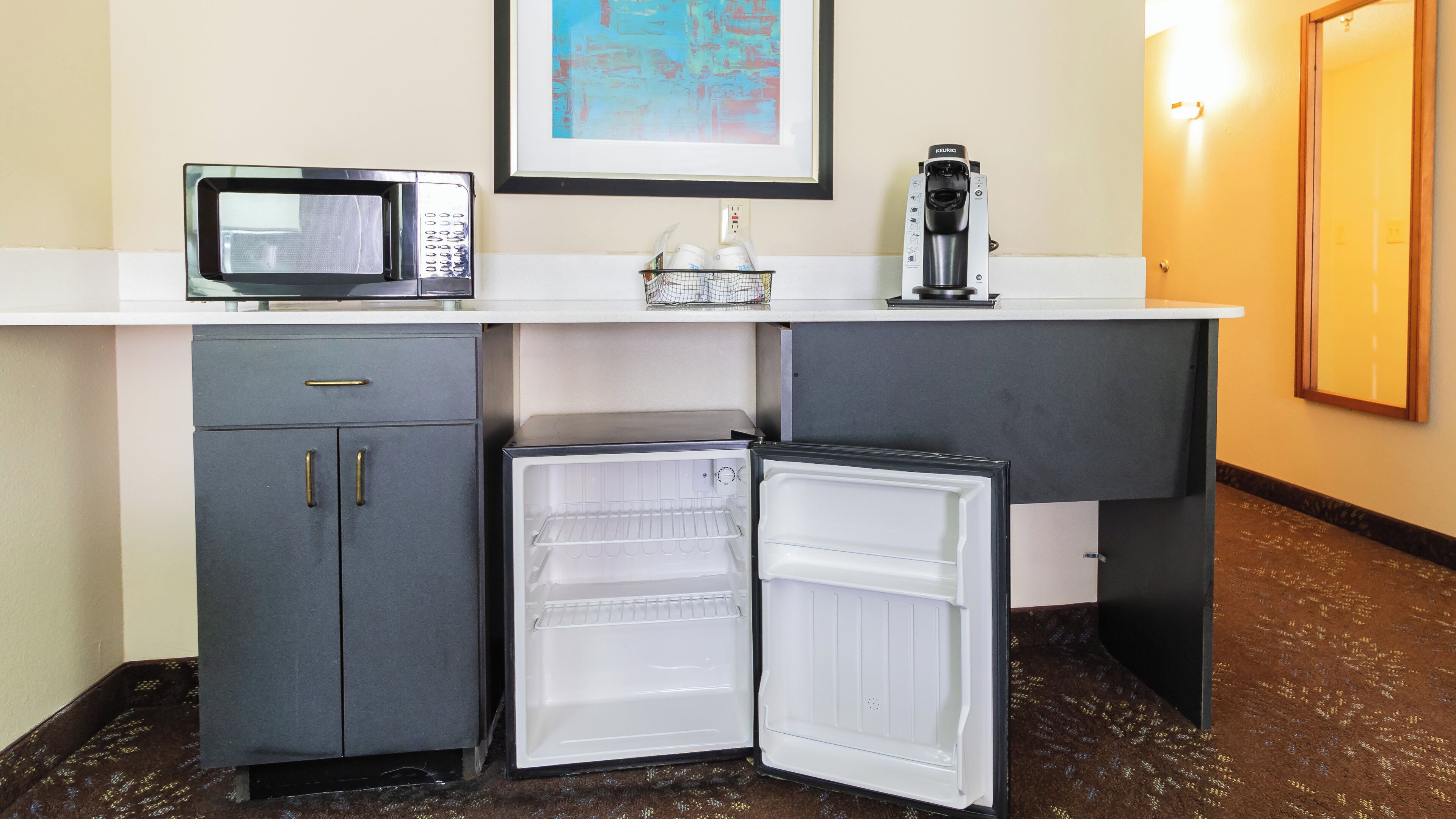A compact kitchenette with a microwave, coffee machine, and a mini-fridge.