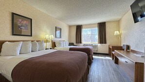A hotel room with two beds, a desk, a chair, a TV, and a window with curtains. - Stay Wise Inn Cedaredge (Cedaredge)