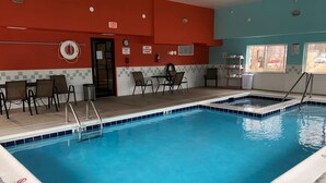An indoor swimming pool with a tiled edge, a lifeguard chair, and a door with an exit sign. - Stay Wise Inn Cedaredge (Cedaredge)