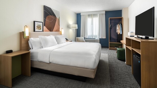 A hotel room with a large bed, bedside tables, a TV, a wardrobe, and a window with curtains. - Spark by Hilton Cedar City (Cedar City)