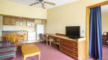 A compact living space with a kitchenette, a dining area, a television, and a blue curtain.