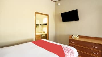 A hotel room with a bed, a dresser, a television mounted on the wall, and a mirror.
