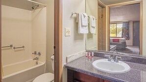Un baño con bañera, inodoro, lavamanos y espejo.