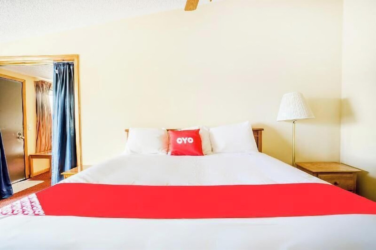 Una habitación de hotel con cama, mesita de noche, lámpara y armario.