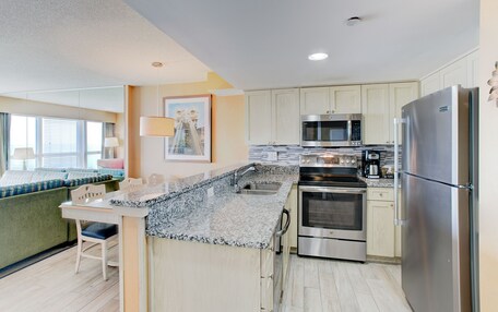 A modern kitchen with granite countertops, stainless steel appliances, and light-colored cabinetry.