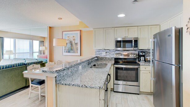 A modern kitchen with granite countertops, stainless steel appliances, and light-colored cabinetry. - Boardwalk Resort and Villas (Virginia Beach)