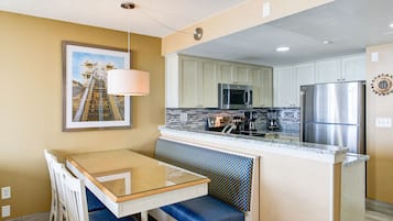 A compact kitchen with a central island, a dining area with a bench, and a wall-mounted picture.
