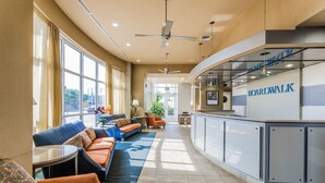 A modern lounge area with a curved counter, seating with patterned cushions, and a view of the outdoors. - Boardwalk Resort and Villas (Virginia Beach)