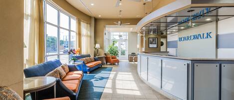 A modern lounge area with a curved counter, seating with patterned cushions, and a view of the outdoors.