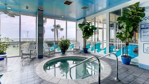 An indoor pool area with clear views of the ocean, seating by the pool, and potted plants. - Boardwalk Resort and Villas (Virginia Beach)