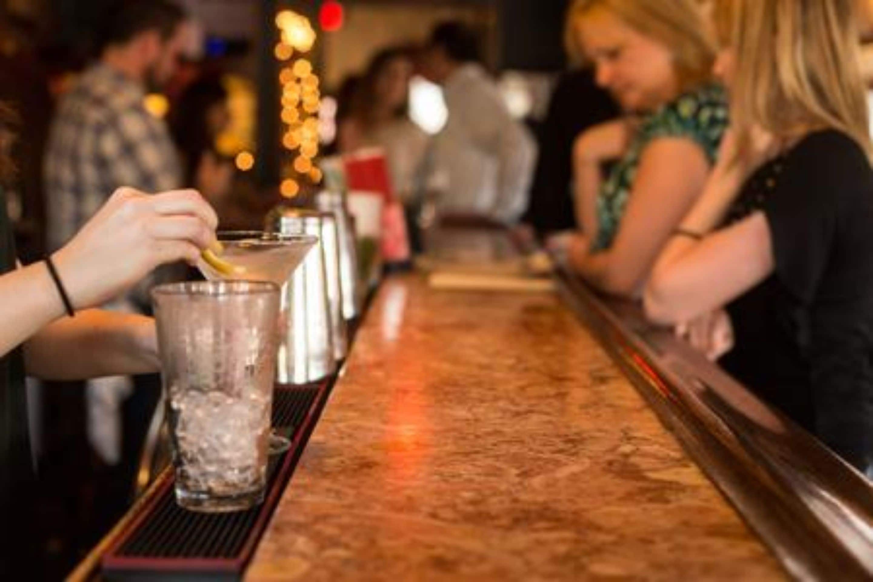 A bar setting with a person preparing a drink.