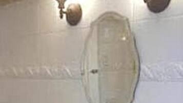 Une salle de bain avec un lavabo blanc, un miroir et un porte-serviettes.