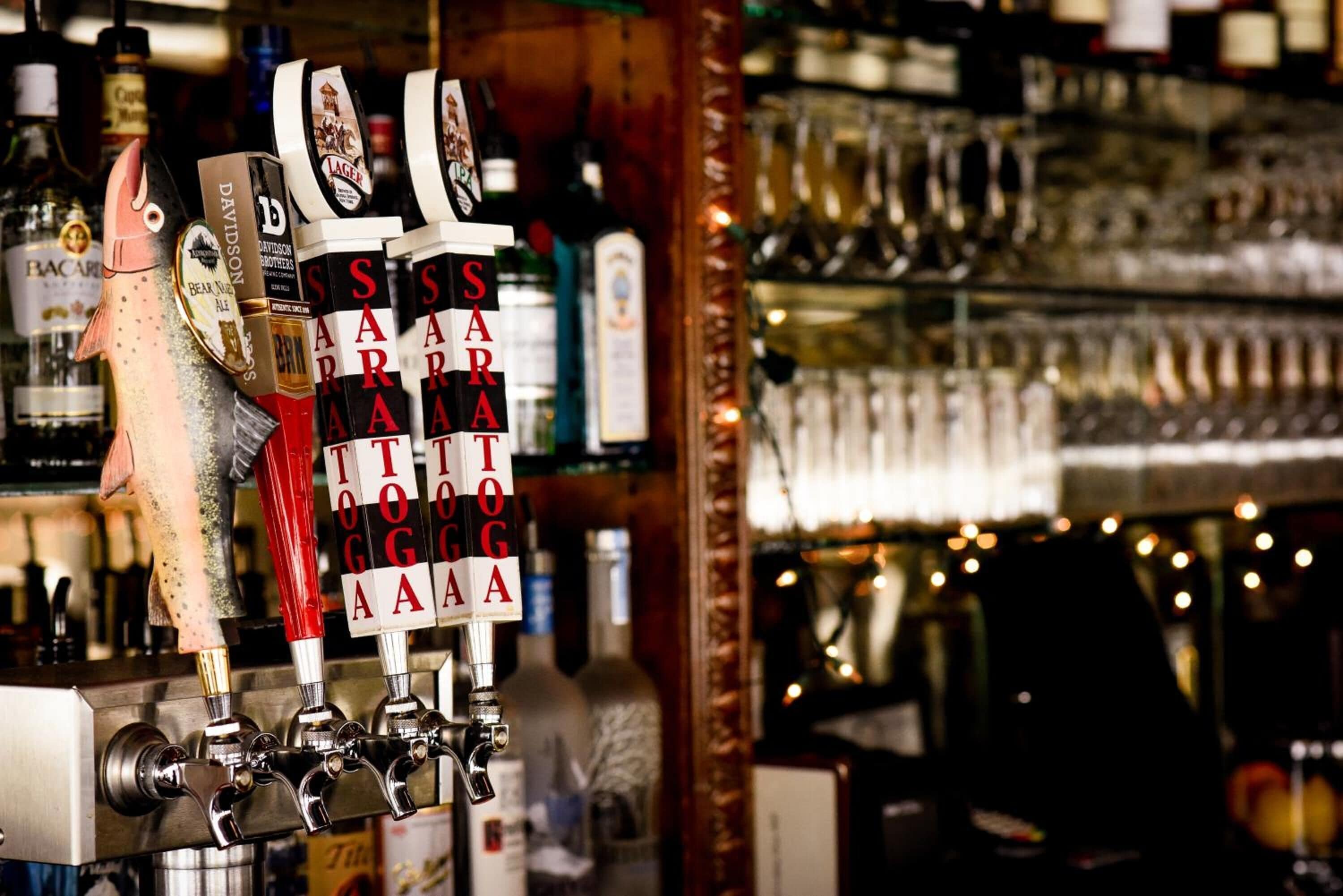 A bar with a fish decoration and multiple beer taps labeled with different brands.