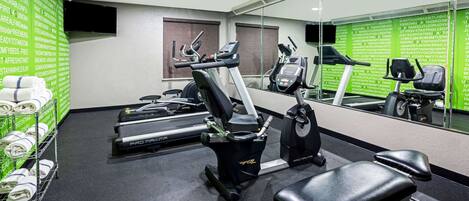 A gym with treadmills, elliptical machines, and a bench.
