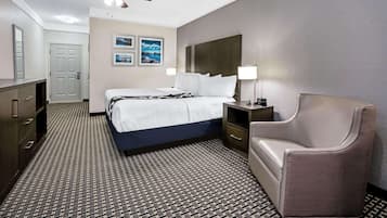 Quarto de hotel com cama, mesa de cabeceira, cadeira, ventoinha no teto e carpete estampado.