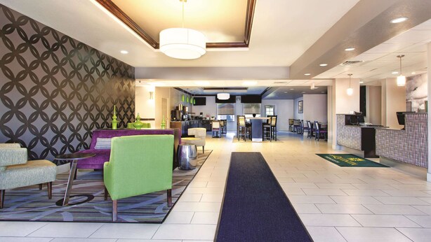 A hotel lobby with a reception desk, seating area, and a patterned wall. - La Quinta Inn & Suites by Wyndham Tampa Bay Area-Tampa South (Tampa)