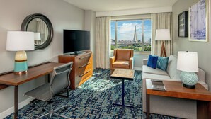 A hotel room with a large window, a sofa, a desk, a chair, a television, and a lamp. - Residence Inn by Marriott Boston Harbor on Tudor Wharf (Boston)