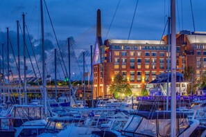 A marina with multiple boats docked, a modern building with a brick facade, and a cable-stayed bridge in the background. - Residence Inn by Marriott Boston Harbor on Tudor Wharf (Boston)