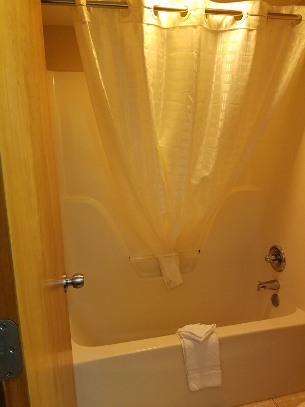 A bathroom with a bathtub, a shower curtain, and a towel hanging on the wall.