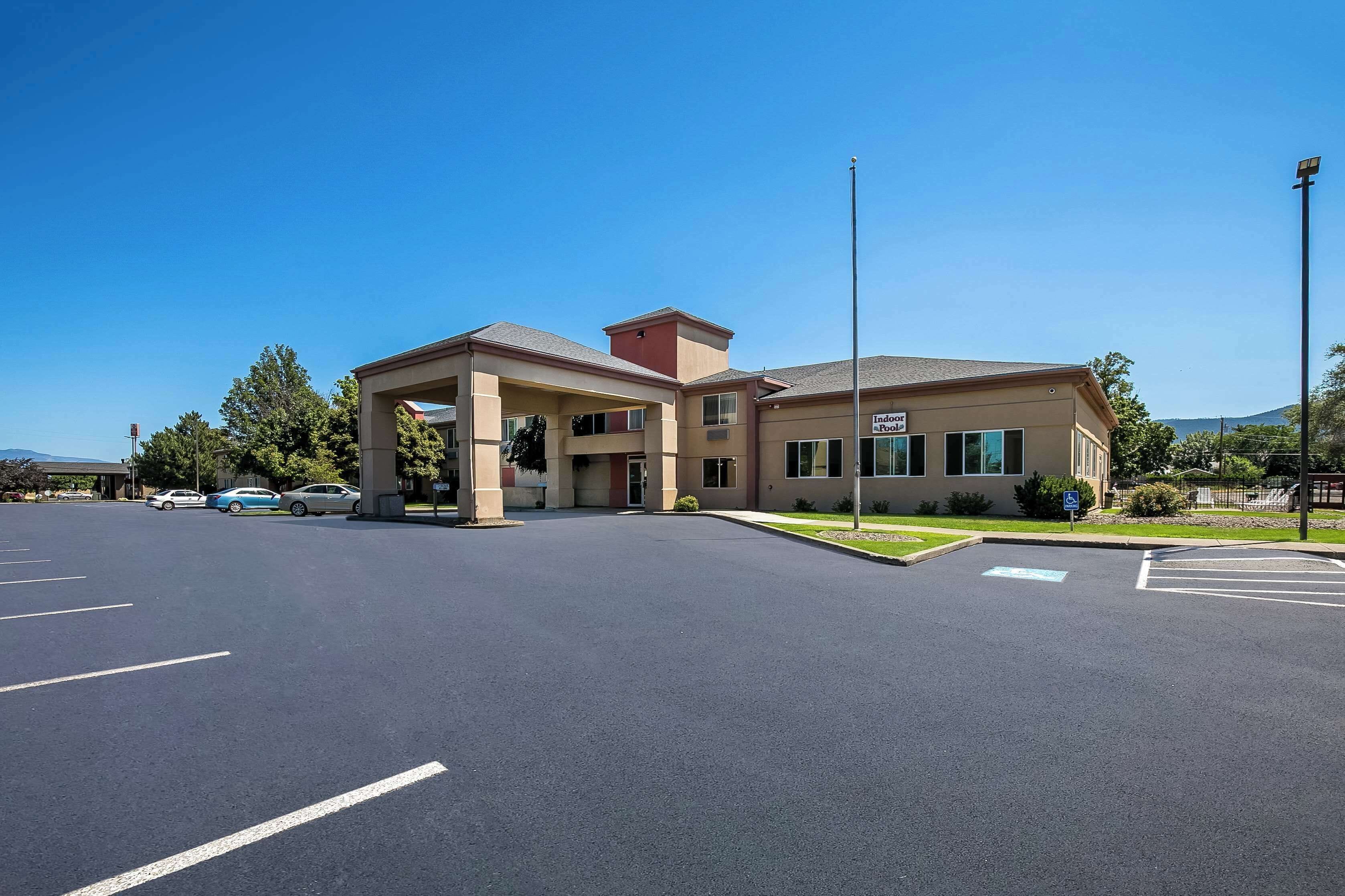 A hotel with a covered entrance, a parking lot, and a sign indicating indoor pool facilities.
