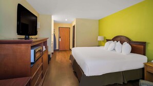 A hotel room with a bed, a television, a desk, and a lamp. - Americas Best Value Sandman Inn (La Grande)