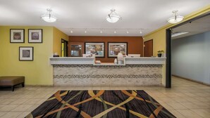 A reception area with a tiled floor, a reception desk, framed artwork on the walls, and a patterned rug. - Americas Best Value Sandman Inn (La Grande)