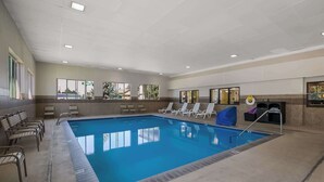 A large indoor swimming pool with clear blue water, surrounded by lounge chairs and a tiled deck. - Americas Best Value Sandman Inn (La Grande)