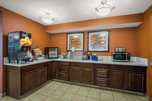 A kitchen with a coffee machine, microwave, and framed pictures on the wall.