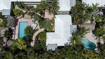 An aerial view of a resort with multiple swimming pools surrounded by lush greenery and palm trees.