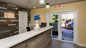 A reception area with a wooden reception desk, a sign reading "Crane's Beach House", and an exit sign above the door. - Crane's Beach House Boutique Hotel & Luxury Villas (Delray Beach)