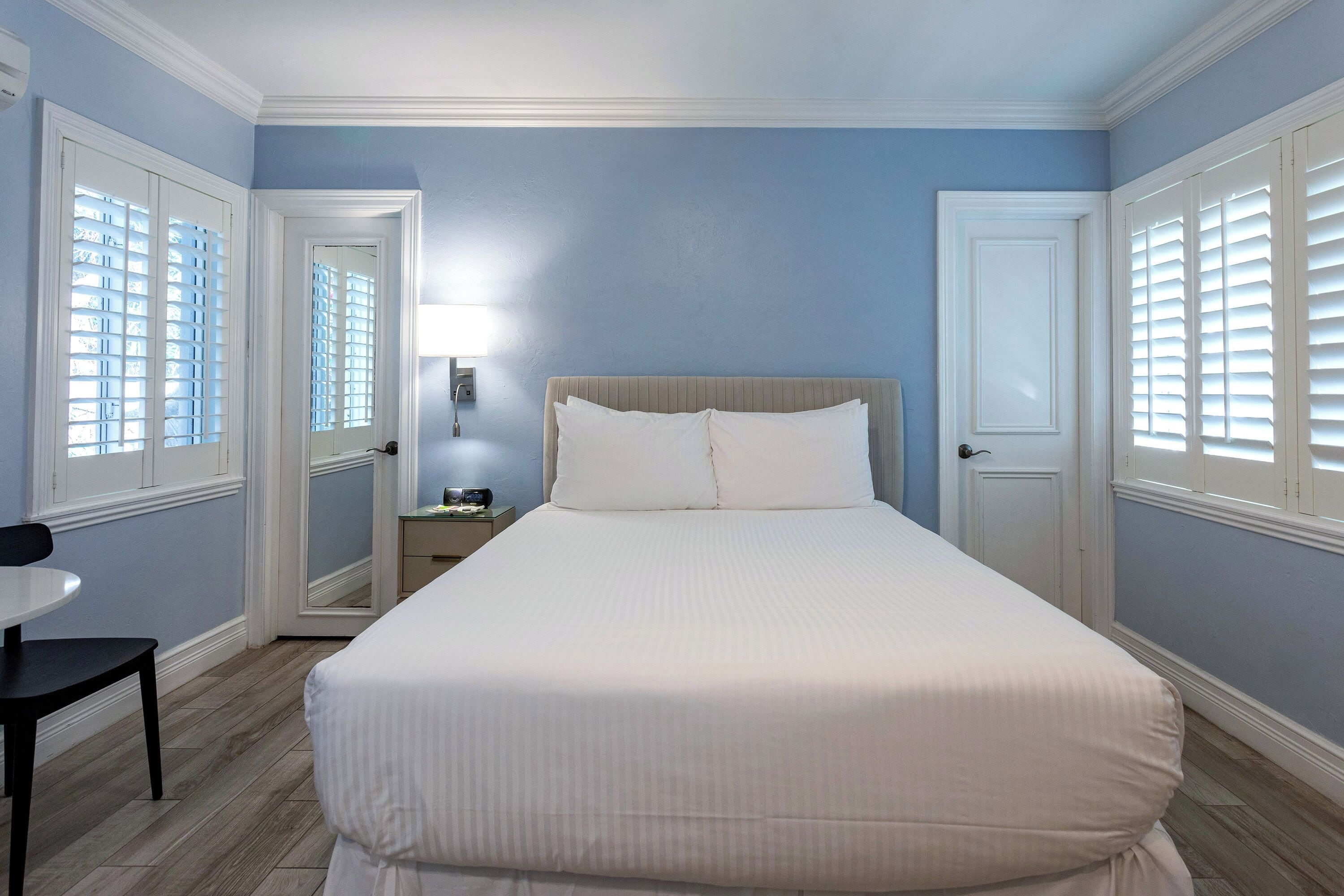 A neatly arranged bedroom with a bed, bedside tables, and a chair.