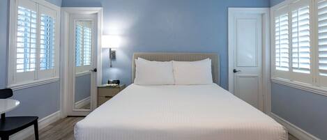 A neatly arranged bedroom with a bed, bedside tables, and a chair.