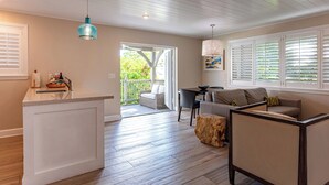 A modern living room with a wooden floor, a white sofa, a dining table, and a kitchen island. - Crane's Beach House Boutique Hotel & Luxury Villas (Delray Beach)