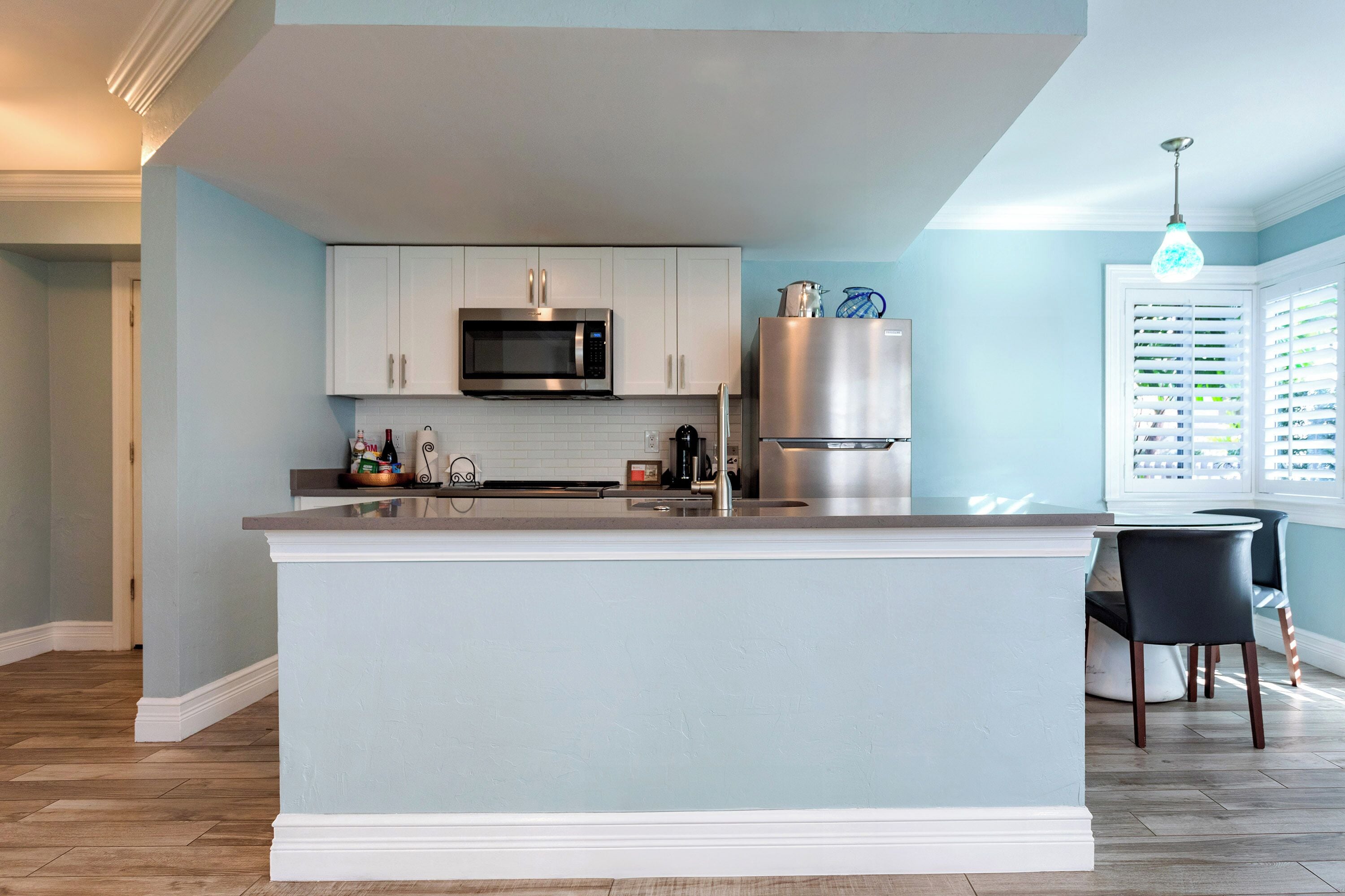 Una cocina moderna con armarios blancos, un refrigerador de acero inoxidable y una isla central.