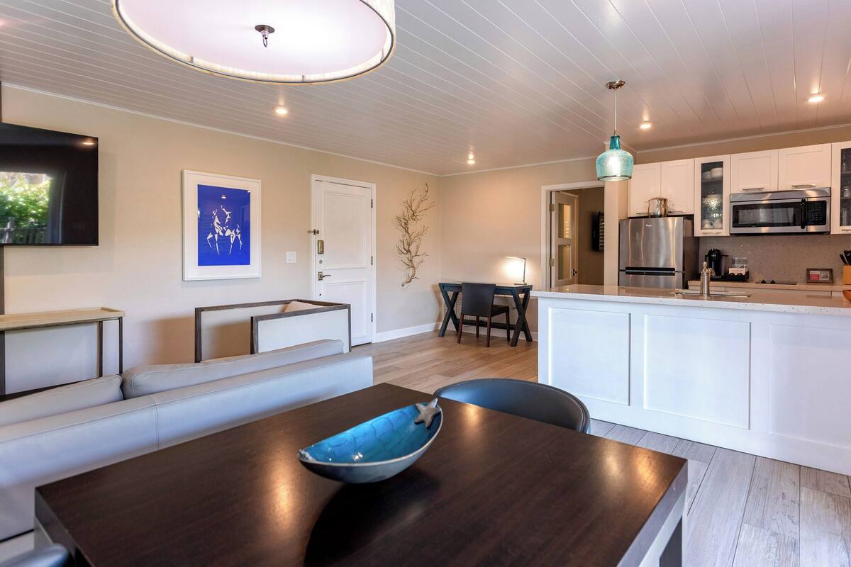 Ett modernt kök med vita skåp, ett kylskåp i rostfritt stål och en inbyggd mikrovågsugn.