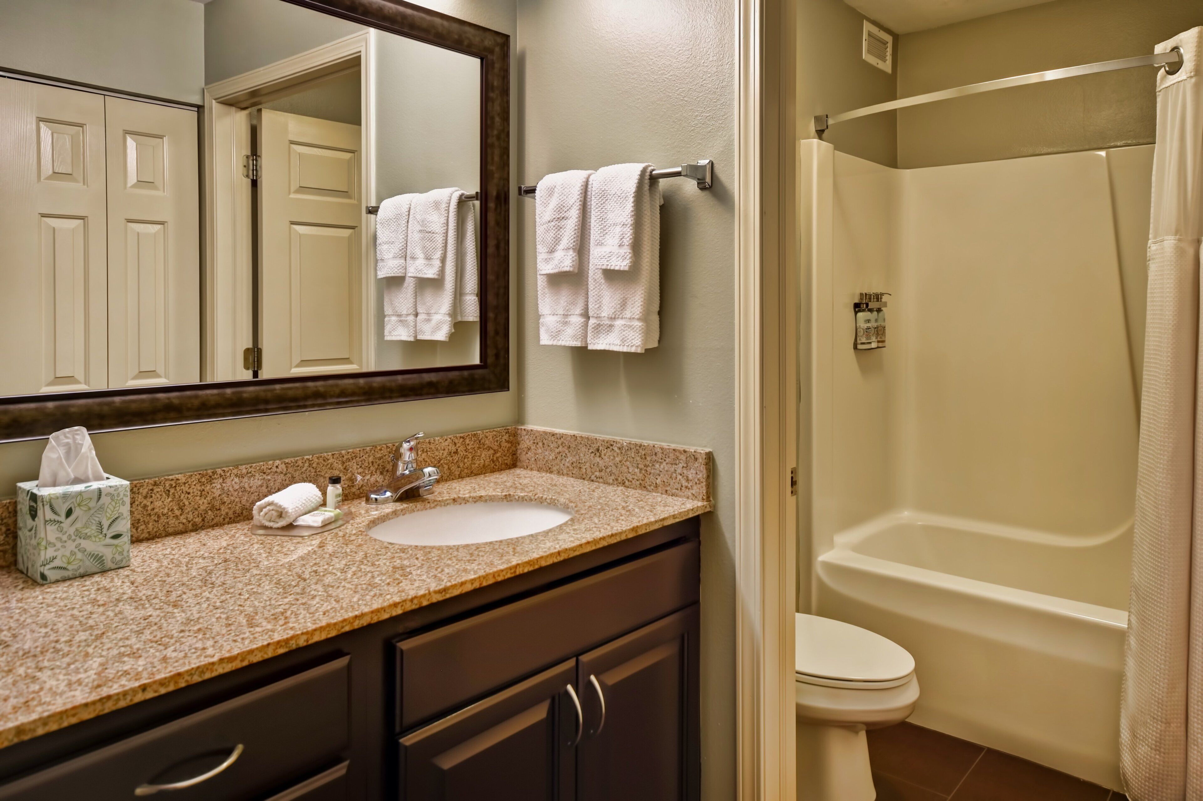 A bathroom with a sink, mirror, towel rack, and a shower area.
